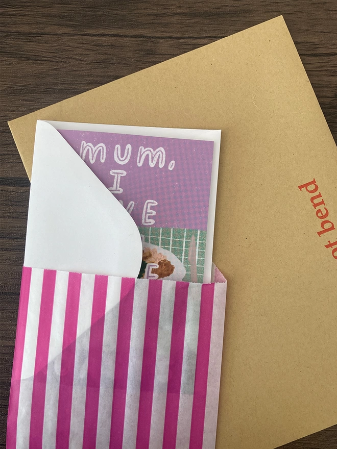 Card packed with a white envelope inside a paper bag