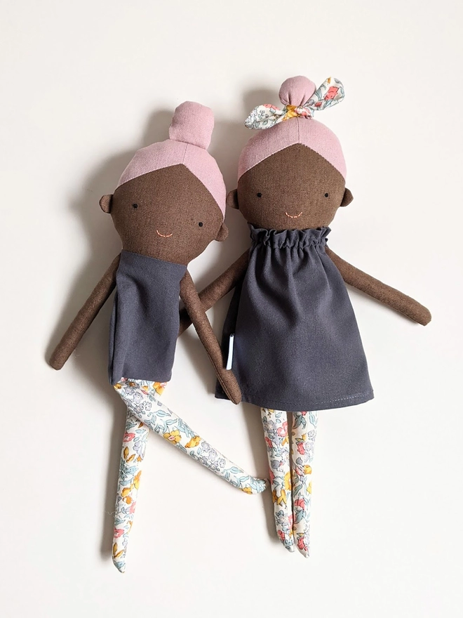 black girl doll with pink hair grey dress and floral tights and bow
