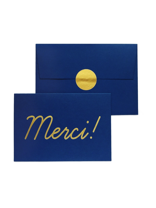 An elegant navy greeting card that says 'Merci!', wth an envelope that has a gold seal