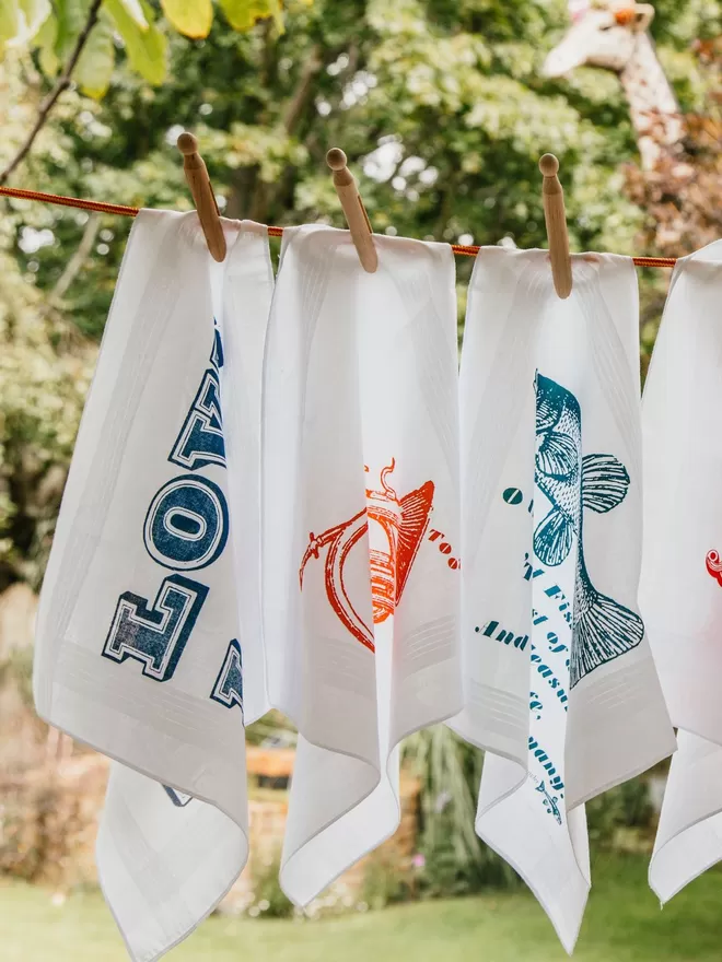 A selection of Mr.PS printed handkerchiefs pegged on a washing line