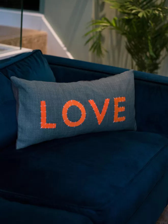 Her Story Cushion - LOVE on a blue sofa.