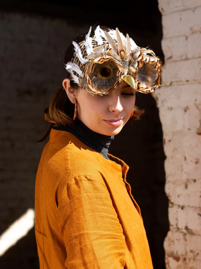 Woman wearing luxury owl party mask atop her head as a headdress