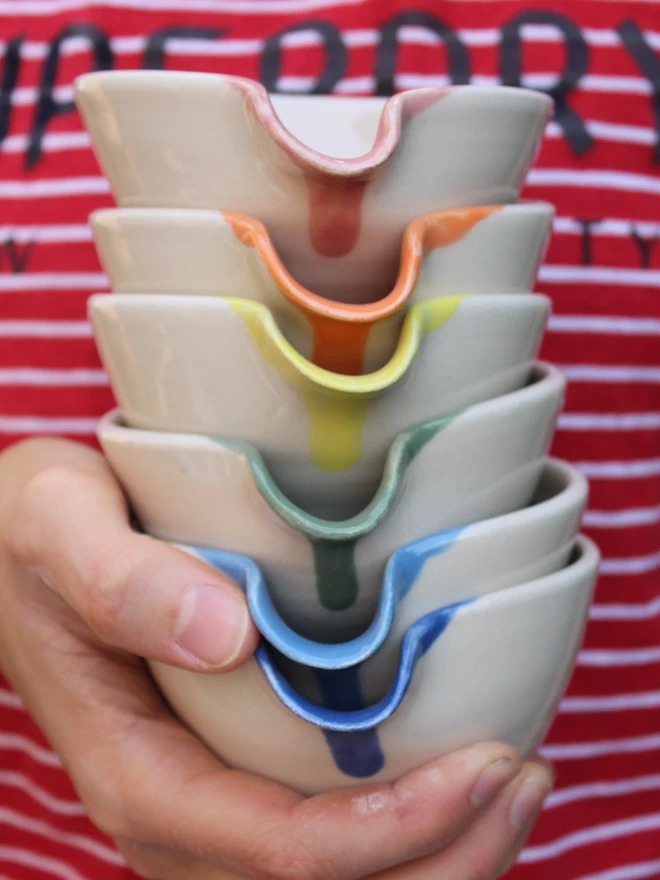 holding a stack of mini ceramic pouring bowls