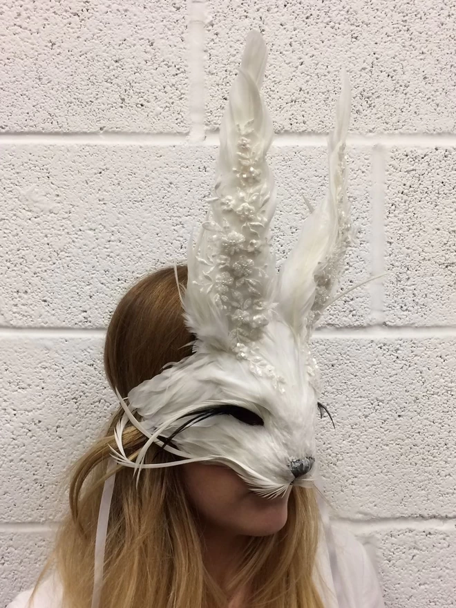 Woman wearing luxury embellished white rabbit masquerade mask over her face