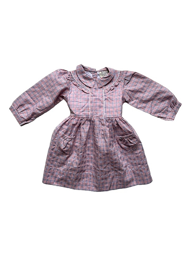 A long-sleeved pink checked seersucker dress with patch pockets on the skirt and ruffle detail at the shoulder.
