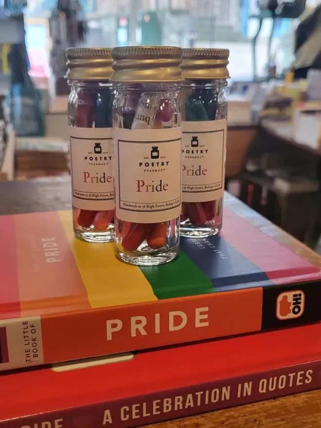 3 Pride pill bottles on stack of books