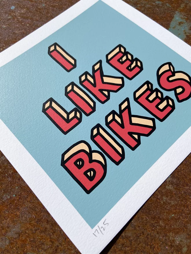 "I Like Bikes" Mini Hand Pulled Screen Print square blue background and the words i like bikes hand drawn then printed on top in red letters and a black outline 