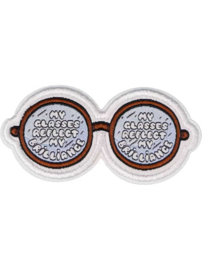 Patch in the shape of glasses. 'My glasses reflect my brilliance' is written on the lenses.