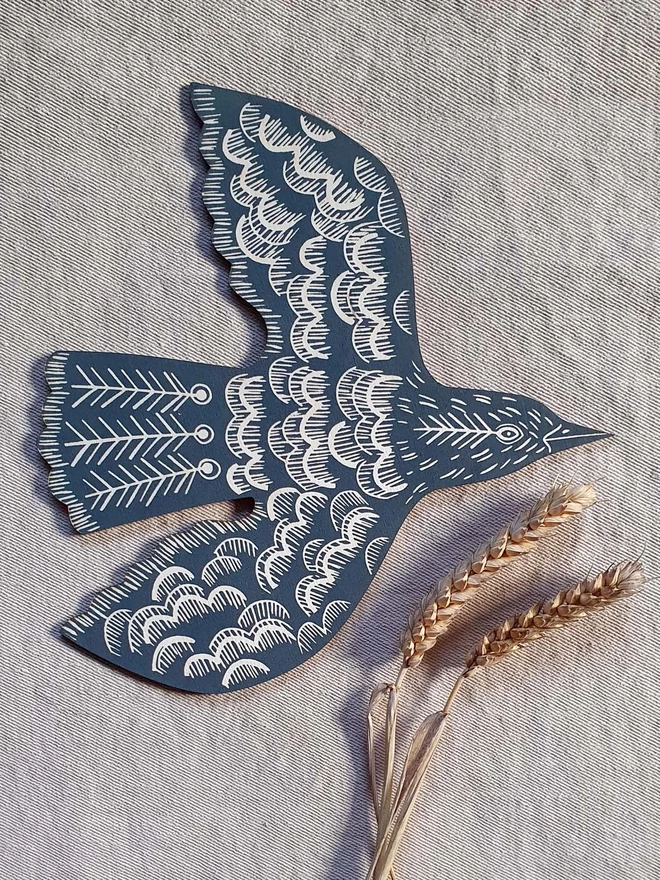 Wall mounted wooden hand printed bird decoration in teal.
