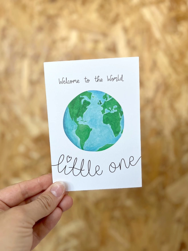 a greetings card featuring an illustration of the earth surrounded by the phrase “welcome to the world little one”
