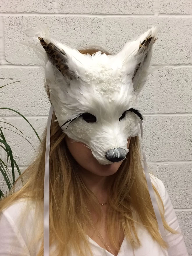 Woman wearing luxury embellished white fox masquerade mask down over her face
