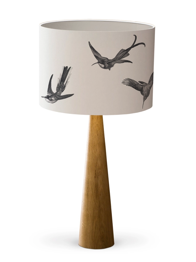 Drum Lampshade featuring hummingbirds with a white inner on a wooden base on a white background