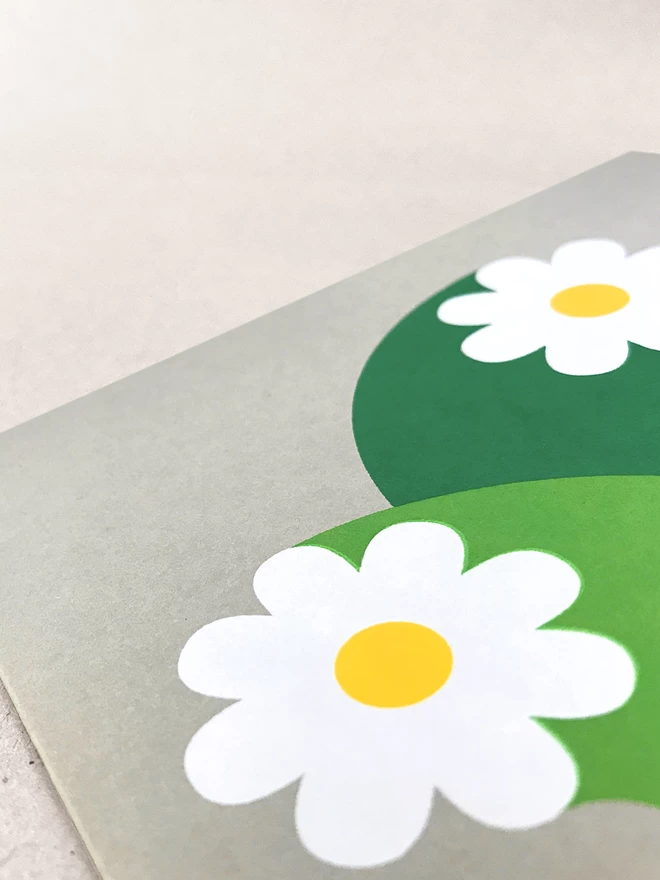 Close up of white flowers with oversized stems screenprinted on grey square card. Laid on a light grey background.