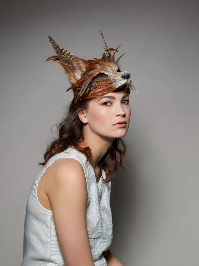 Woman wearing a luxury red fox masquerade mask atop her head as a headdress