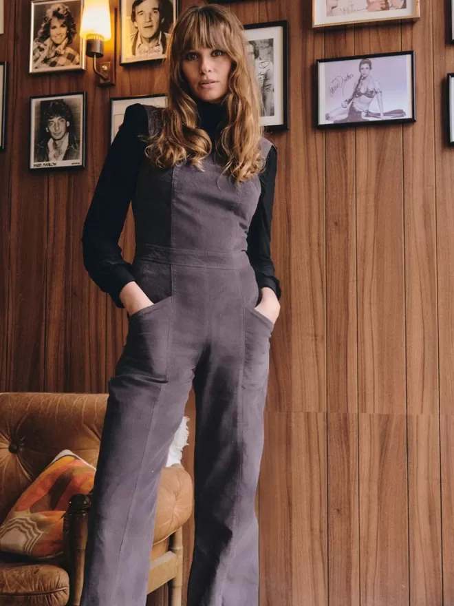 Model wearing the new sienna dungarees in cord in a living room against a wooden wall