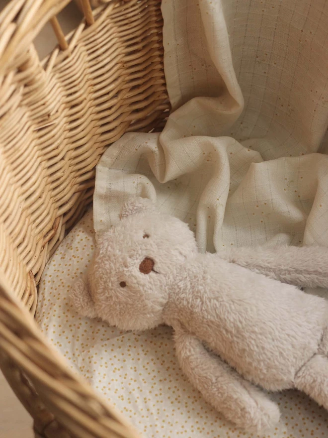 A stuffed toy in a changing basket covered with muslin swaddle