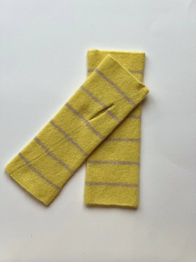 Yellow knitted wristwarmers laid flat overlapping each other