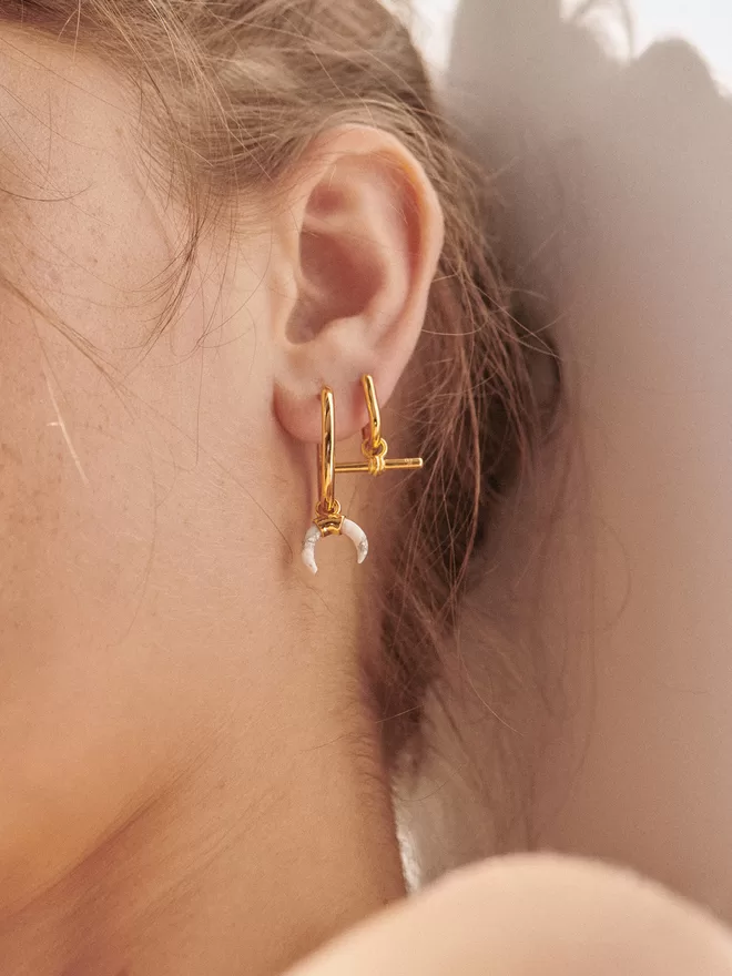 woman wearing earrings with gold charms