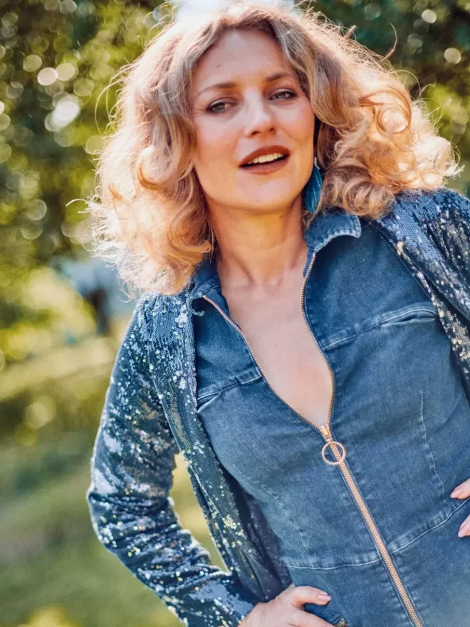 model wearing ruby denim jumpsuit with long sleeves paired with a sequin long cardigan outside