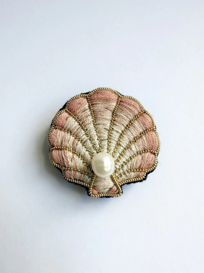 Clam shell brooch with pearl on a white background 
