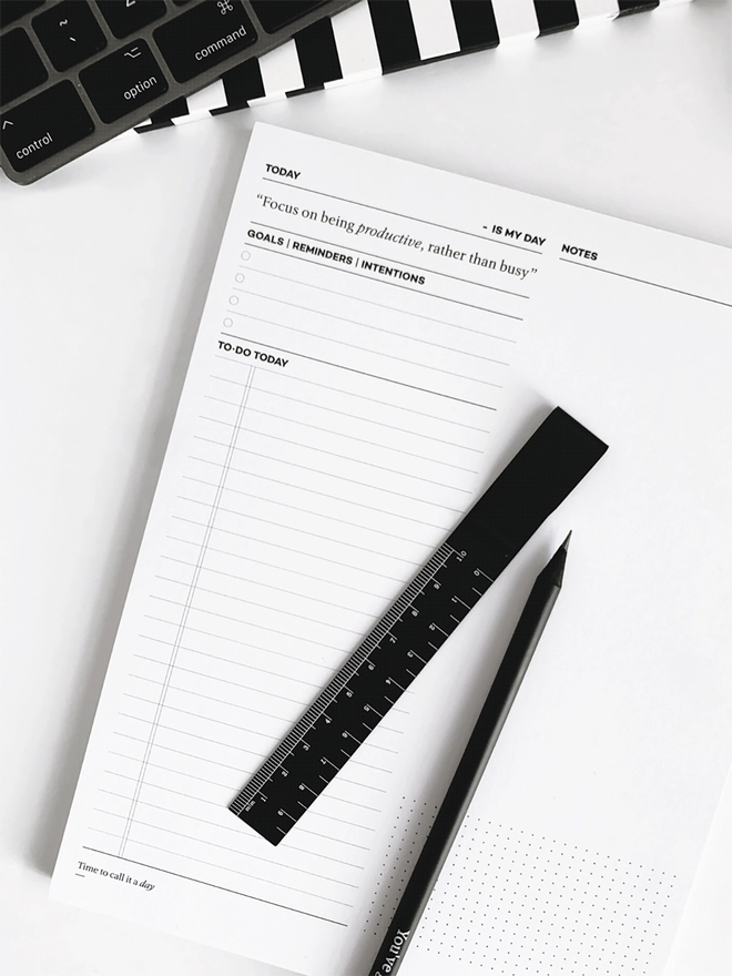 Daily Productivity Desk Pad with a black ruler and black HELLO TIME pencil laid on top.