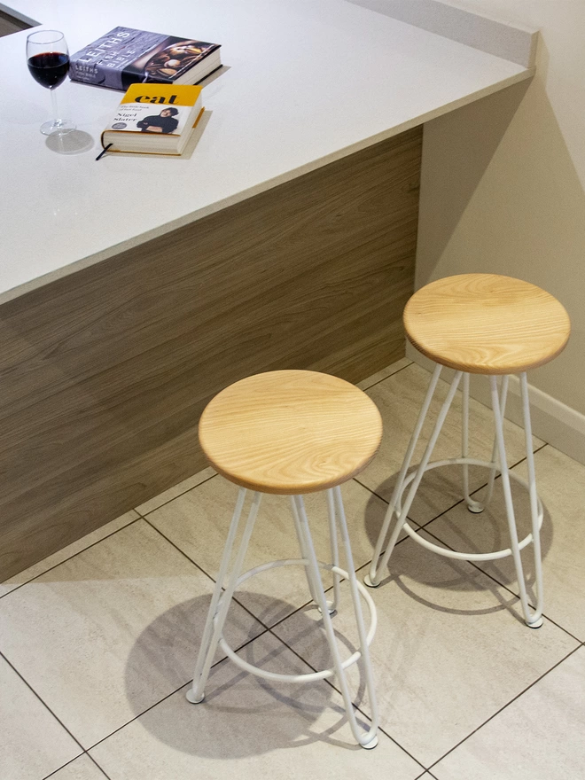 pair of hairpin leg bar stools against a kitchen counter, with white hairpin legs and ash seats