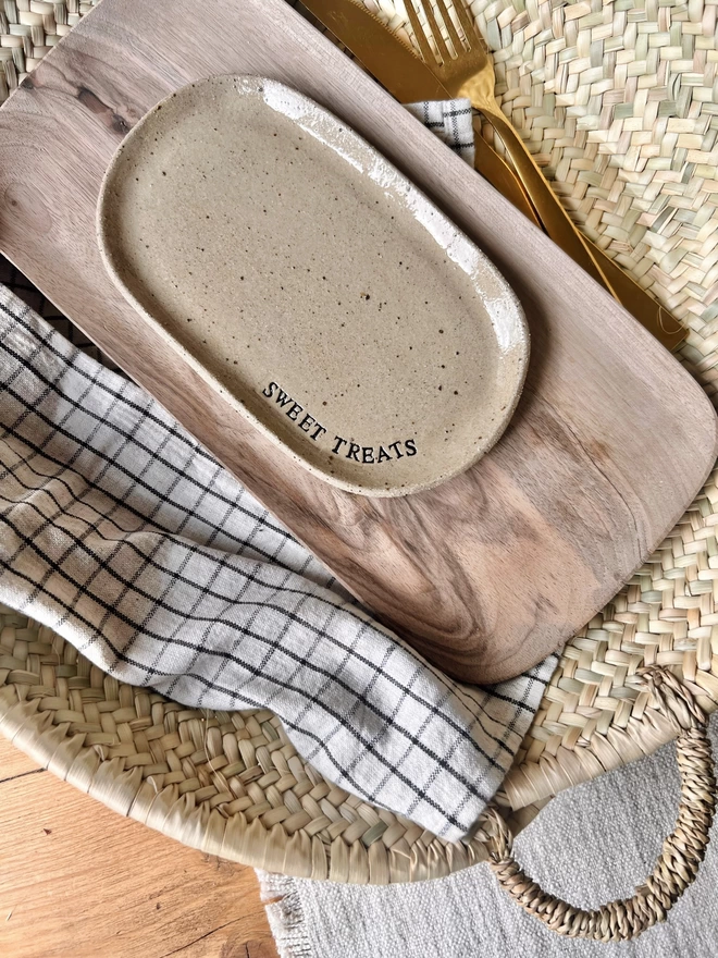 Oval ceramic plate, with the words 'Sweet Treats' stamped around the edge, laid on a wooden tray