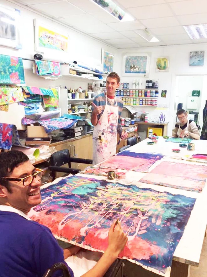 2 artists painting orginal Underwater artwork in studio with blues and reds for charity chocolate bar