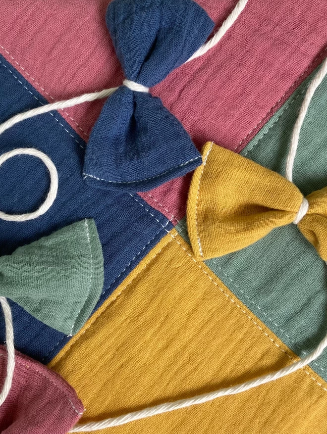 Close up image of the quilted kite wall hanging in pink, navy, green and ochre by Cooper and Fred.