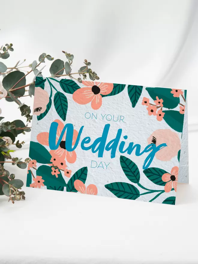Seeded Paper Greeting Card featuring floral illustrations with ‘On Your Wedding Day’ written in the centre with a bunch of flowers in the background