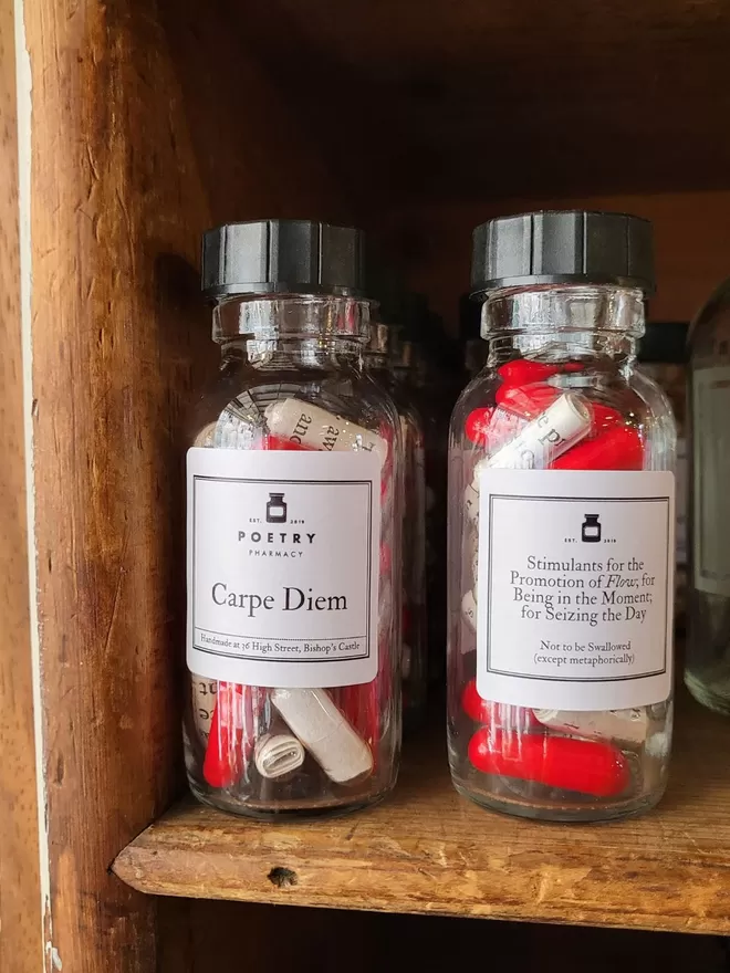 bottles of red and white Carpe Diem poetry pills in a row on a shelf