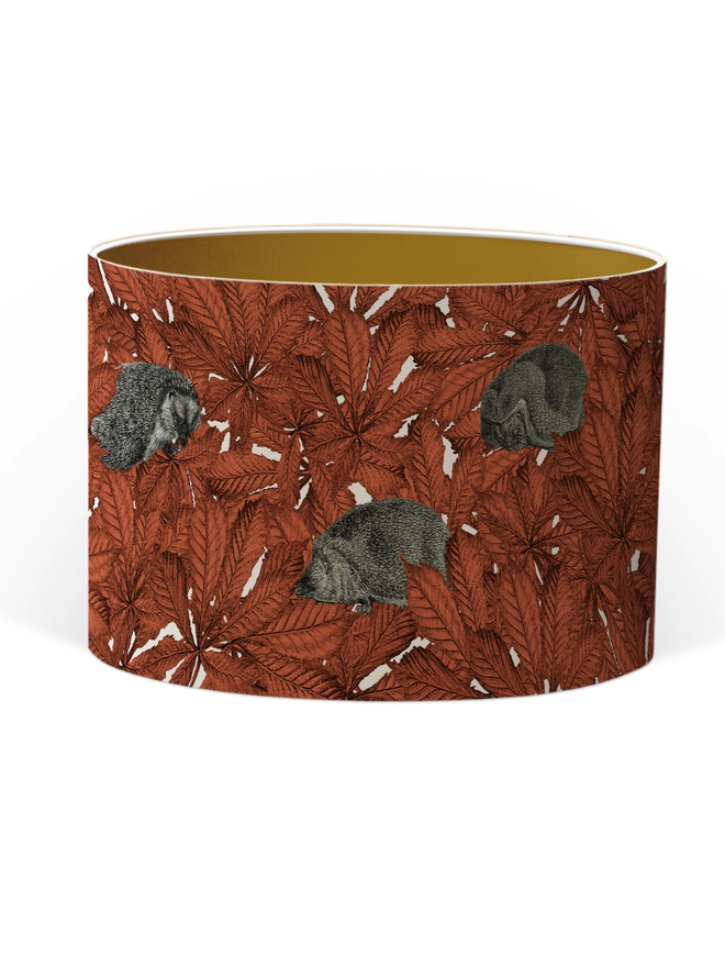 Drum Lampshade featuring hedgehogs in autumnal russet red leaves with a Gold inner on a white background