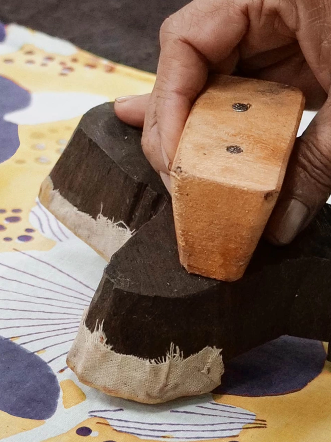 Hand holding a wooden block to print fabric