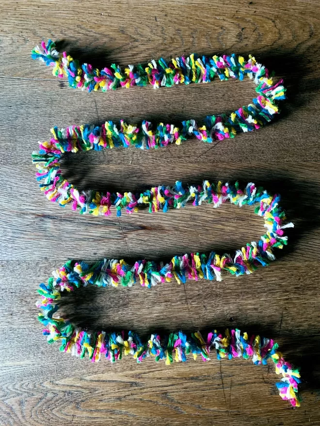 Multicolour neon jute string tinsel AKA Strinsel laid out in a looped zig zag on an oak table