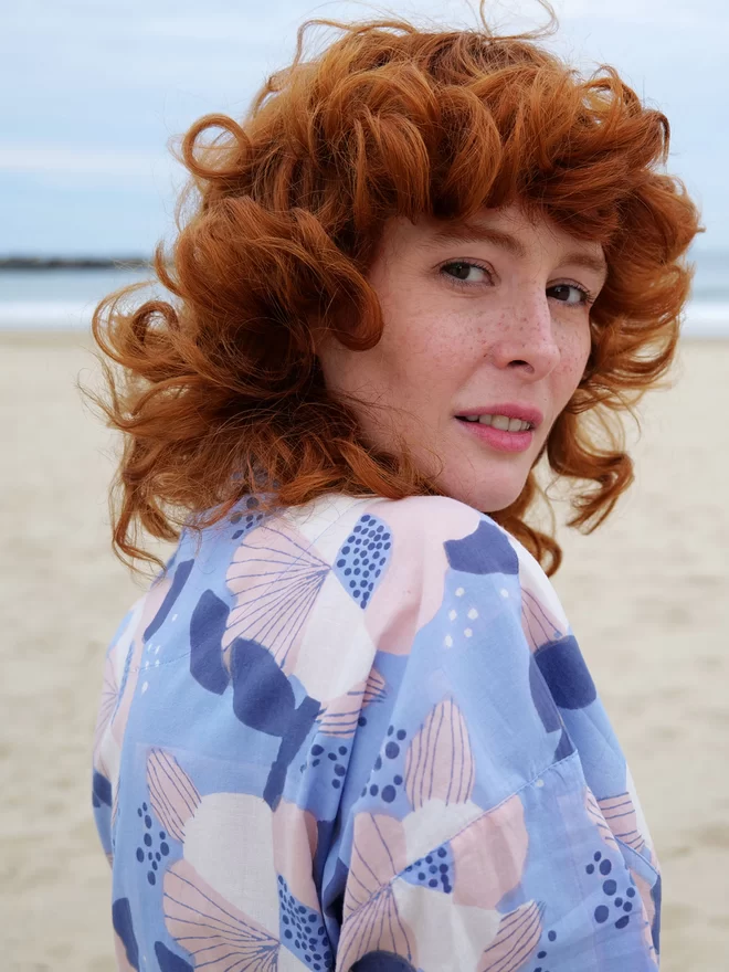 Close up of block printed robe in large scale floral design worn by red head girl on the beach