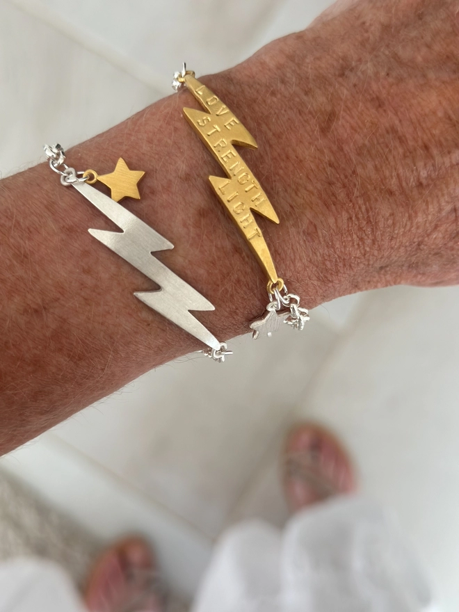 model wears a personalised gold lightning bolt charm on a silver belcher chain bracelet with a silver mini star