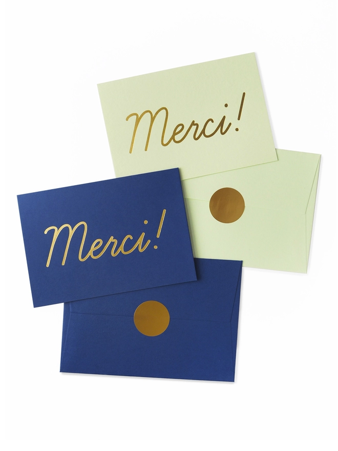 An elegant greeting card that says 'Merci!', wth an envelope that has a gold seal, available in Navy and Mint Green