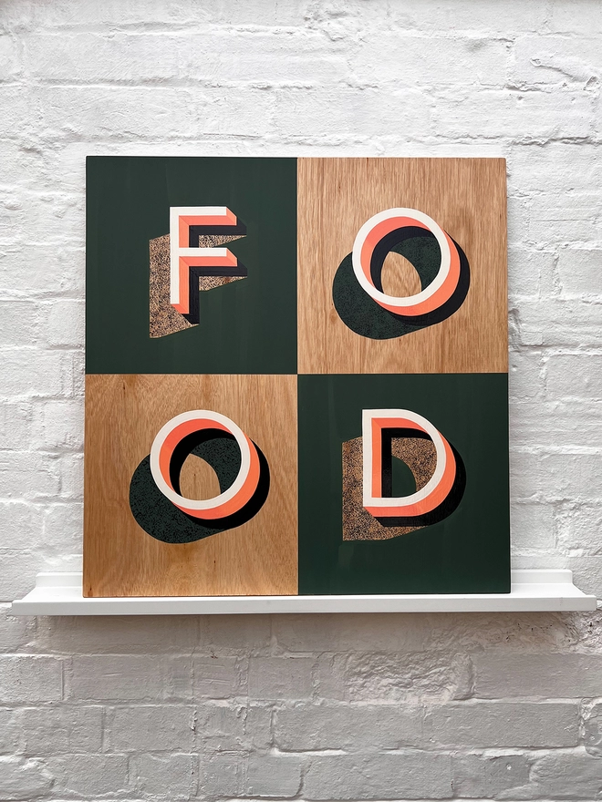 FOOD hand painted sign in coral, green and aubergine, against a white brick wall, straight on 
