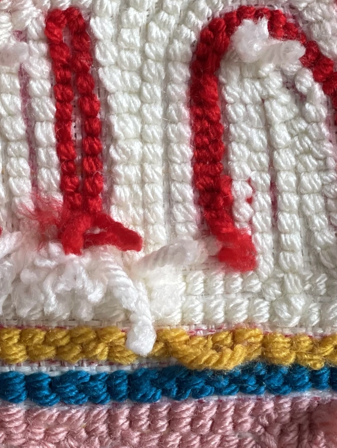 red, cream, mustard, blue and pink stitches of wool