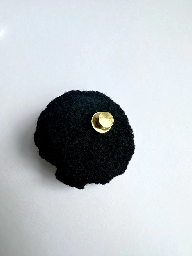 Plain black felt back of the brooch with a gold fastener on a white background 