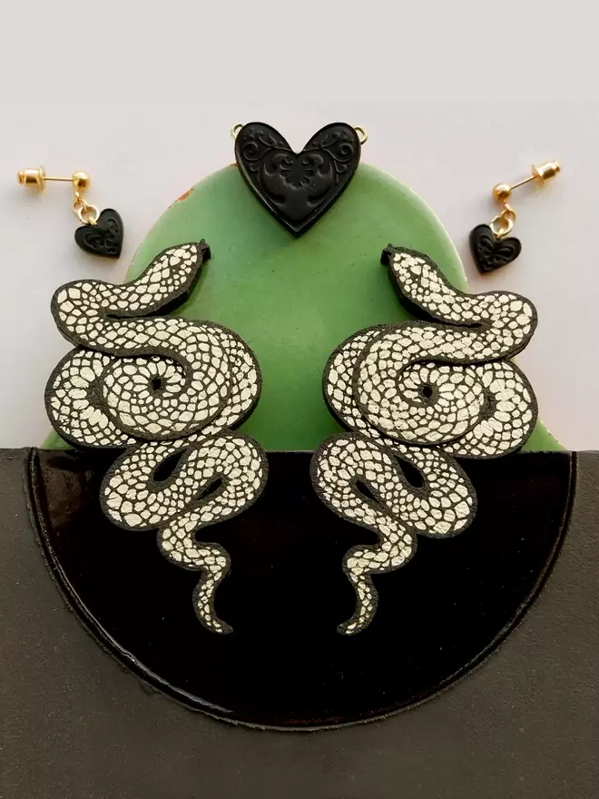 large gold & black serpent earrings , green & black background