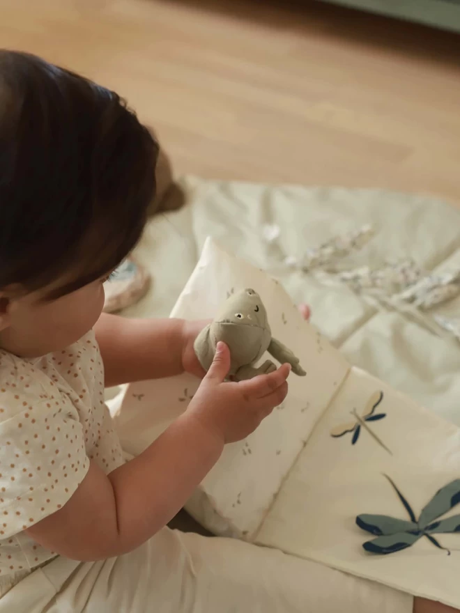 A baby playing with fabric book about tales of the riverbank