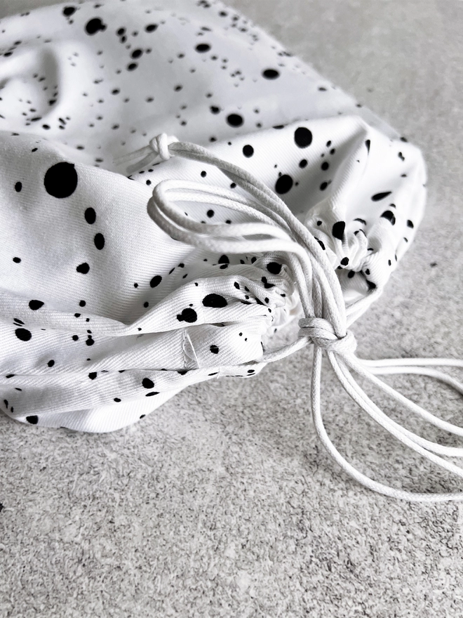 Close up of the black and white drawstring bag containing a HELLO TIME planner.
