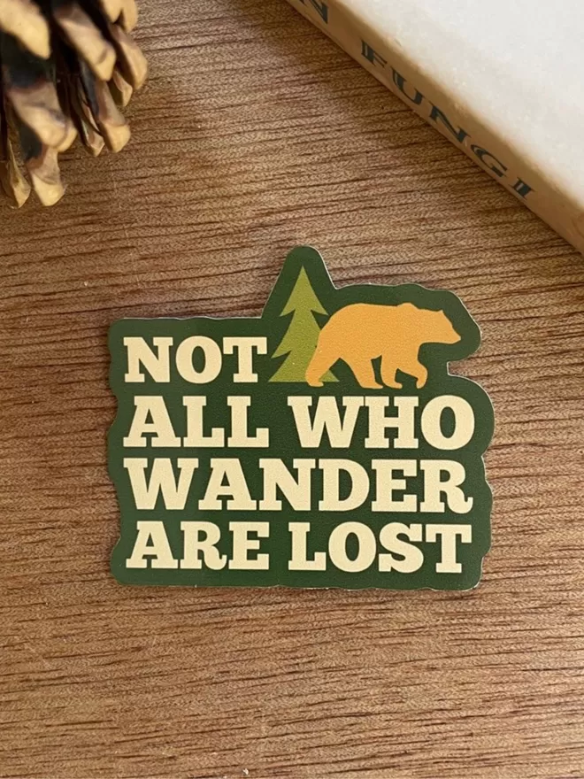 Not All Who Wander Are LOst Adventure Sticker on a wooden table.