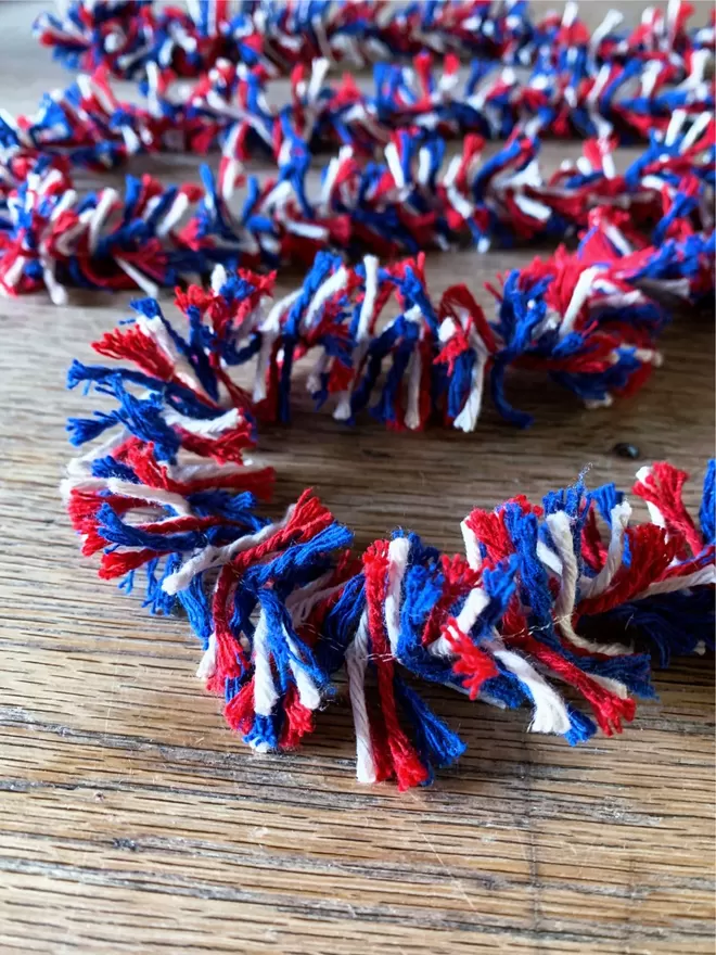 Close up of Right Royal Strinsel. Red white and blue string tinsel on an oak table.