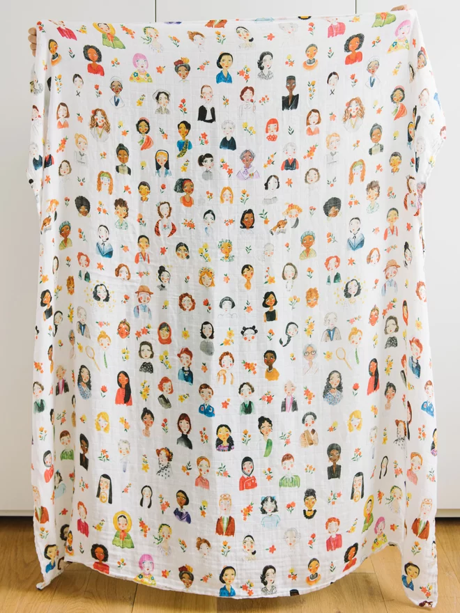 opened up cotton bamboo swaddle blanket showing portraits of 96 iconic women 