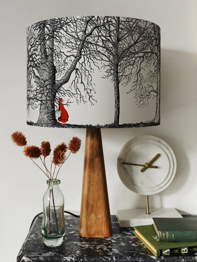 Drum Lampshade featuring Red Riding Hood on a wooden base on a shelf with books and ornaments