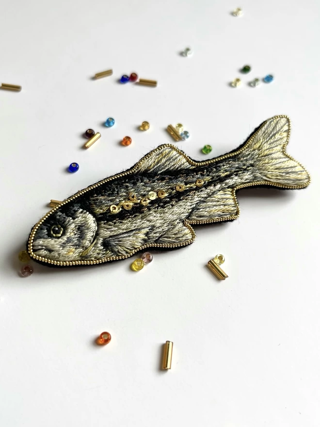 Minnow Brooch on background with beads