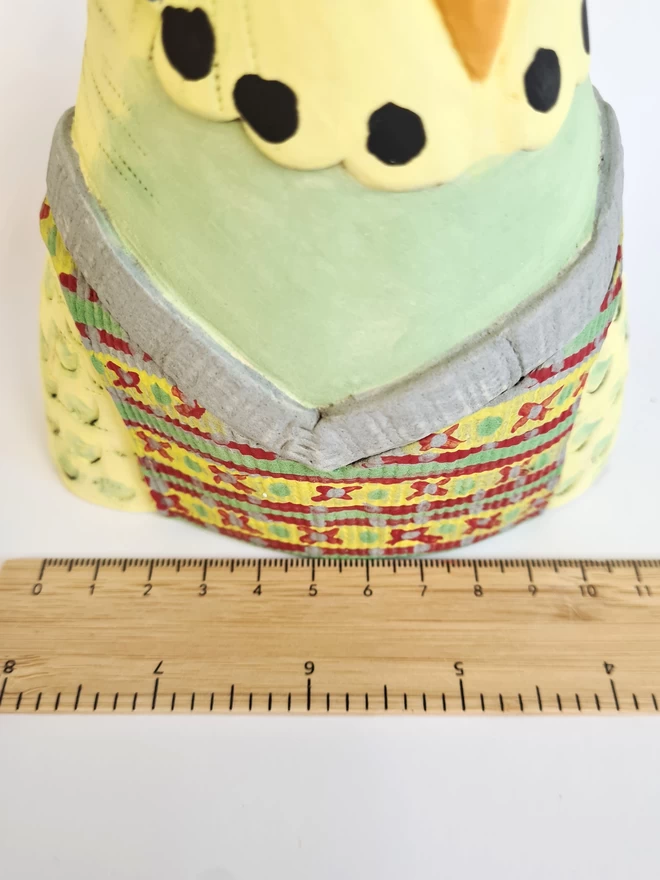 Charlotte Miller handmade ceramic Granville the Budgie seen with a ruler for scale.