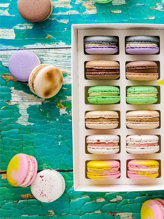 colourful macarons in a white box on a green table